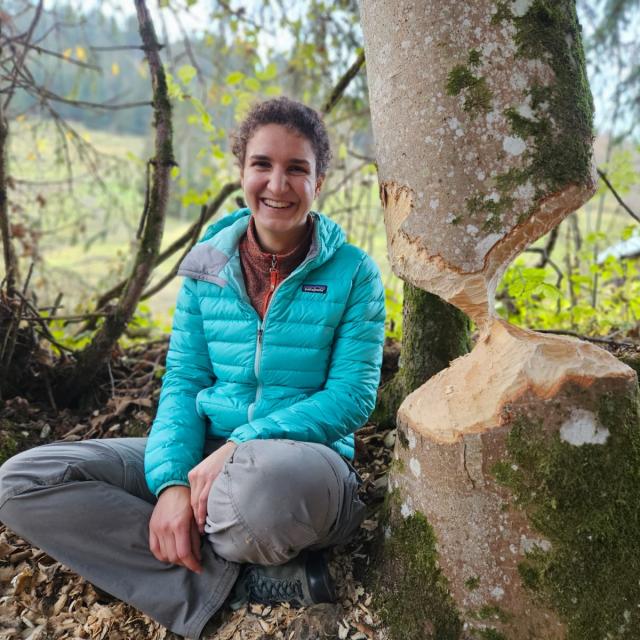 Femme à côté d'un tronc d'arbre avec des traces de castor